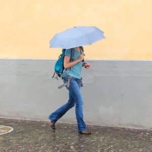 Girl walking with umbrella on rainy day in town