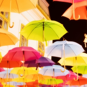 Multi coloured umbrellas against a black sky and building in the background