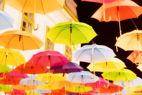 Multi coloured umbrellas against a black sky and building in the background