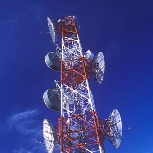 A red and white communications mast against a blue sky