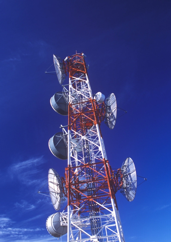 A red and white communications mast against a blue sky