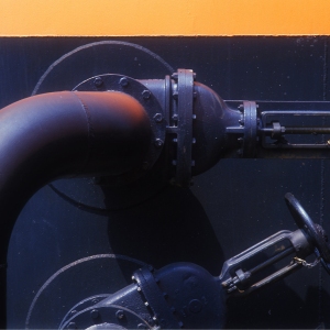 Valves and pipework on a large chemical or oil storage tank at a dockside tank farm