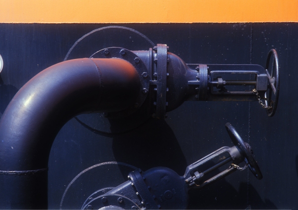 Valves and pipework on a large chemical or oil storage tank at a dockside tank farm