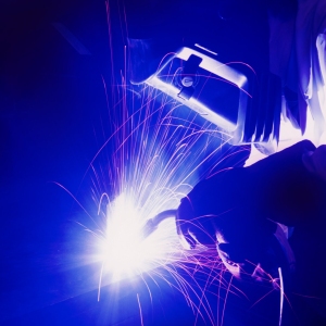 A welder working in the dark, with mask and gloves