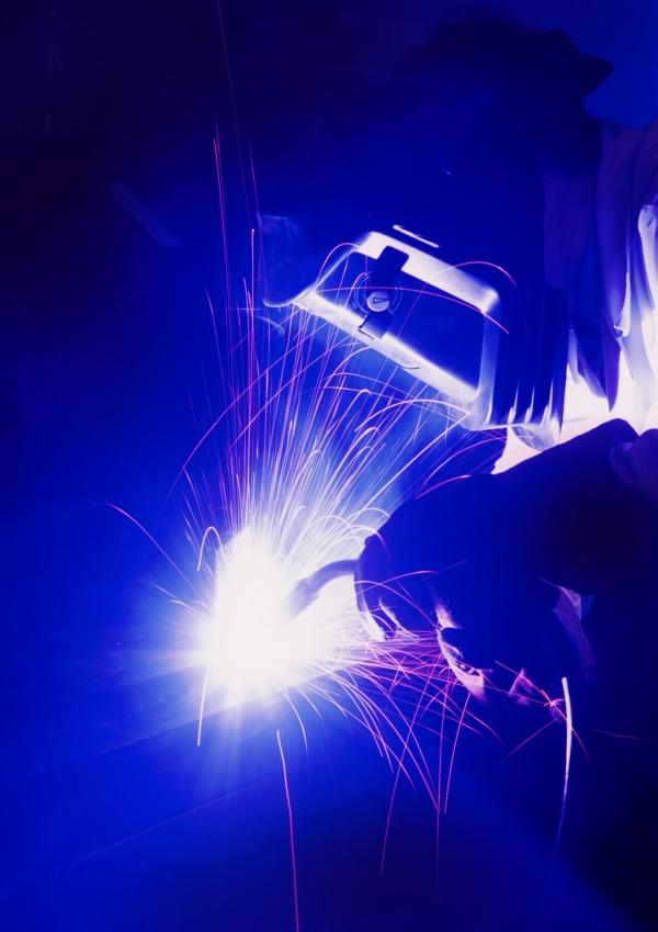 A welder working in the dark, with mask and gloves