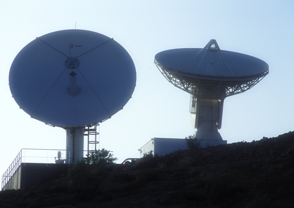 Two satellite dishes silhouetted on a remote hilltop