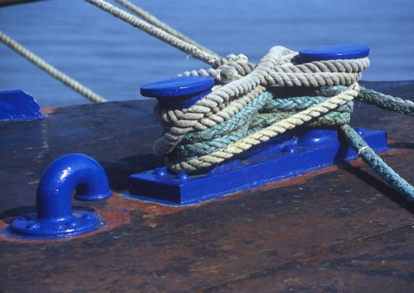 Blue capstans with thick moring ropes on the dockside