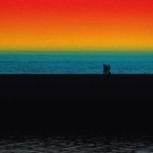 A group of walkers walking on the shoreline with wild colours in the sky