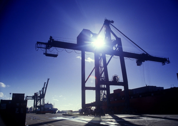 Dockside cranes silhouetted against the sun