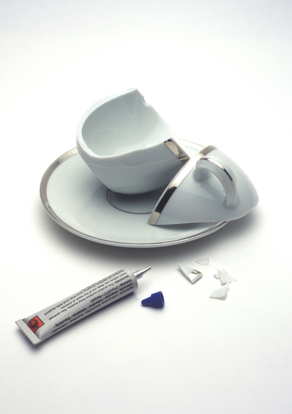 An image of an expensive but broken cup and saucer with a tube of superglue