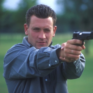 A man or security officer training or practicing with an automatic pistol on the gunnery range