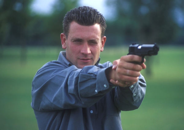 A man or security officer training or practicing with an automatic pistol on the gunnery range