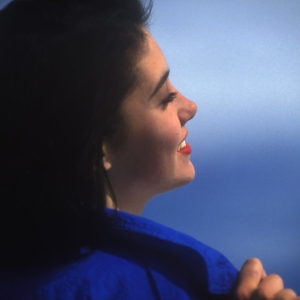 Young woman smiling against a blue sky