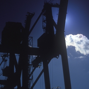 Silhouettes of dockside cranes against the afternoon sun or sunset