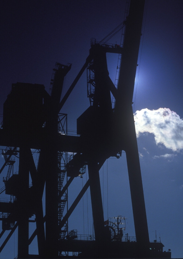 Silhouettes of dockside cranes against the afternoon sun or sunset