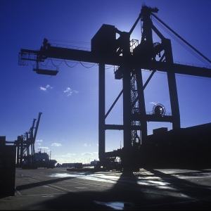 Silhouetted dockside cranes on the waterfront against the afternoon sun