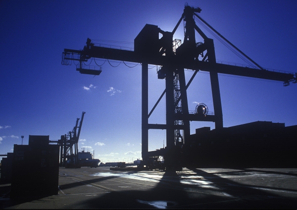 Silhouetted dockside cranes on the waterfront against the afternoon sun