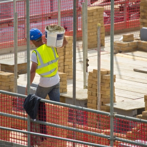 A building site worker or hod carrier or labourer carrying some cement in a bucket