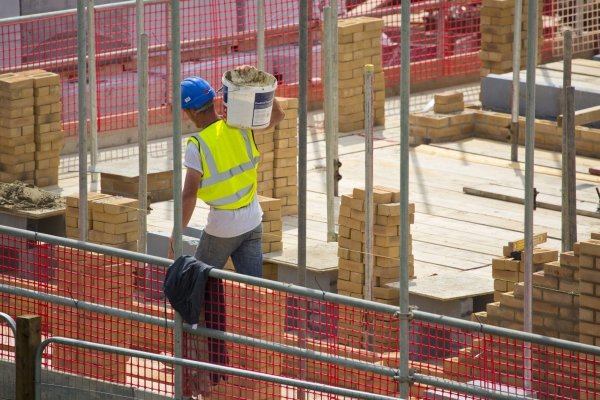 A building site worker or hod carrier or labourer carrying some cement in a bucket