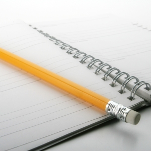 A close up macro view of a wire bound notebook and pencil