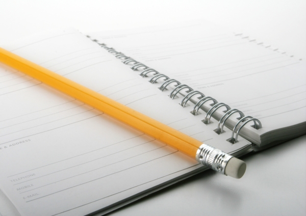 A close up macro view of a wire bound notebook and pencil