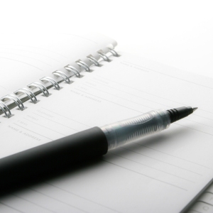 A close up macro view of a wire bound notebook and pen