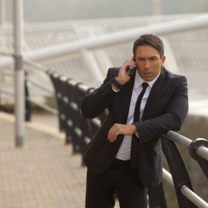 A muscular looking man in a suit talking earnestly on his mobile. Could be taking instructions, could be security, checking emails etc.