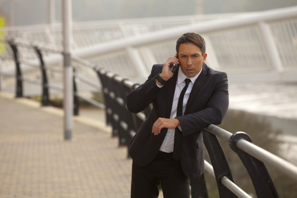 A muscular looking man in a suit talking earnestly on his mobile. Could be taking instructions, could be security, checking emails etc.