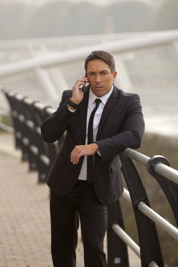 A burly looking security man or business man talking on the phone