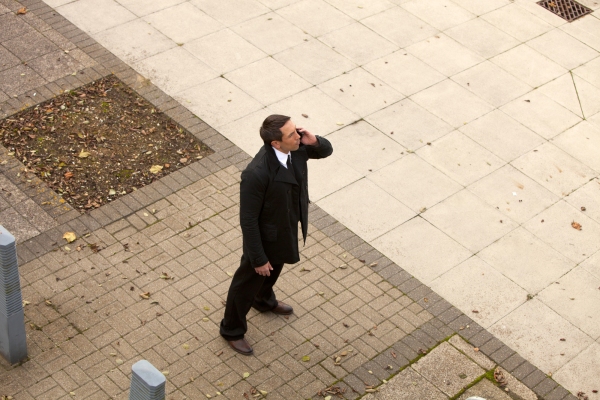 A security guard on the mobile and looking upwards