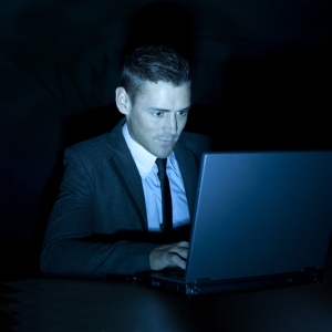 a man working on a laptop computer during the night or in a darkened room