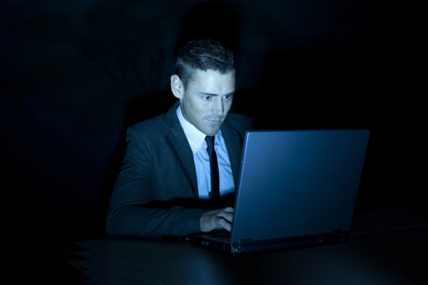 a man working on a laptop computer during the night or in a darkened room