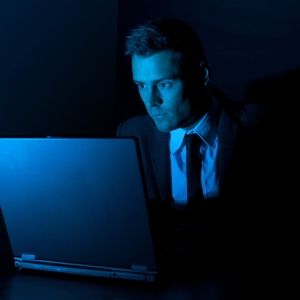 A man working on a laptop computer in the dark