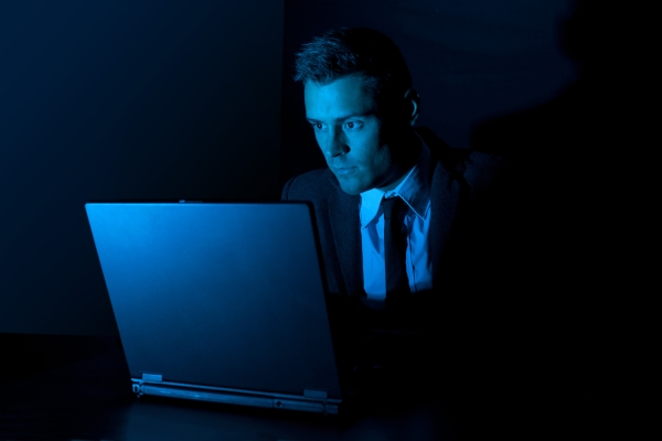 A man working on a laptop computer in the dark