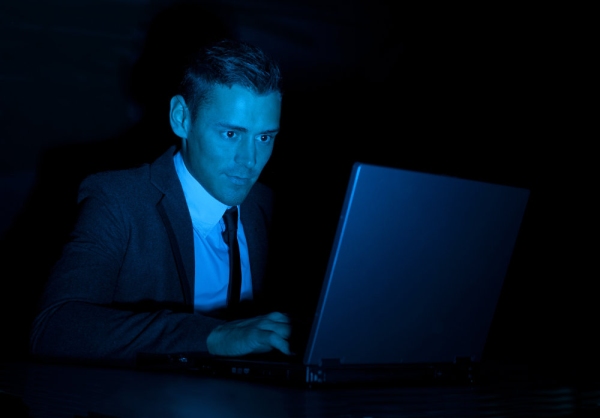 a man working on a laptop computer during the night or in a darkened room