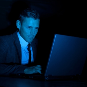 a man working on a laptop computer during the night or in a darkened room