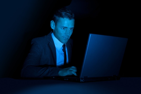 A man working on a laptop computer in the dark