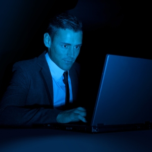 A man working on a laptop computer in the dark