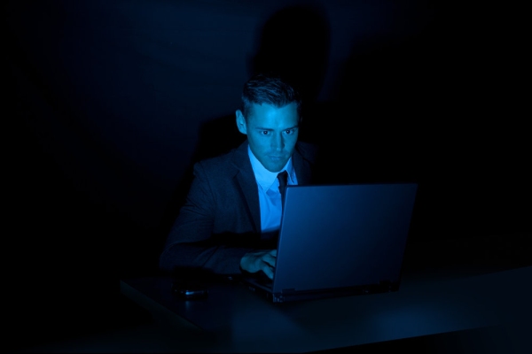 Man operating a laptop computer with a dark background