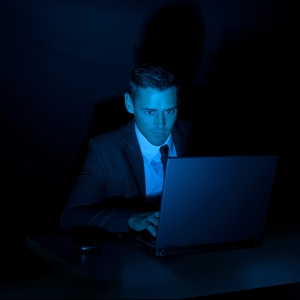 Man operating a laptop computer with a dark background