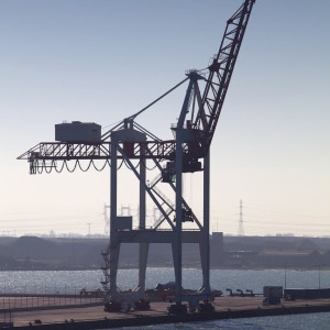 A single dockside crane silhouetted against the late afternoon light