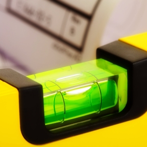 Close up of a yellow spirit level with out of focus plans in the background