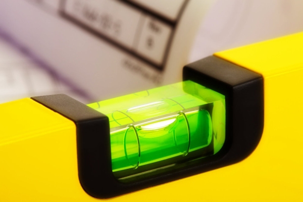 Close up of a yellow spirit level with out of focus plans in the background