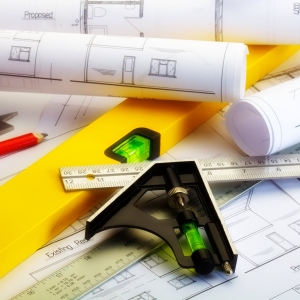 Close up image of plans for a house with ruler, spirit level and square