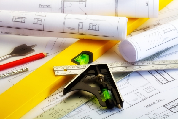 Close up image of plans for a house with ruler, spirit level and square