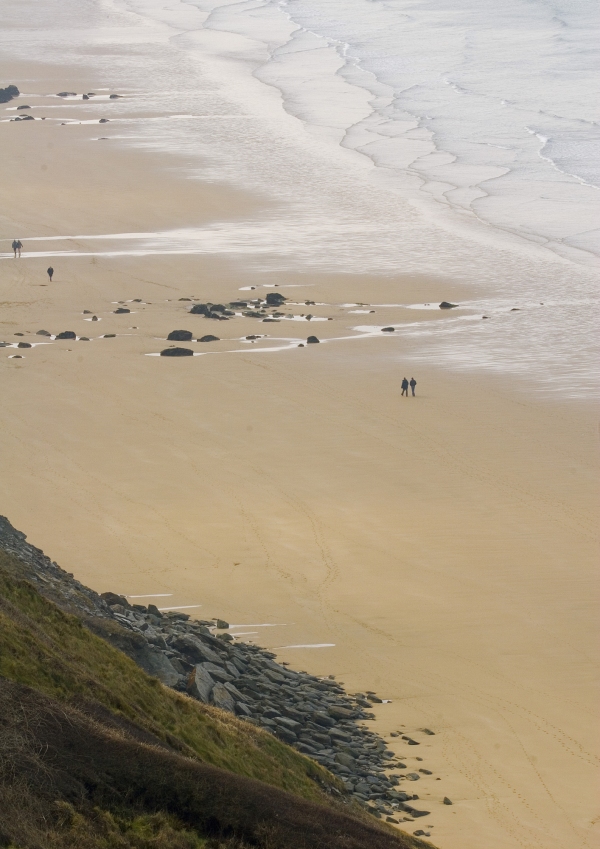 Distant walkers on a big, sandy beach