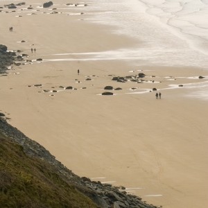 Distant walkers on a large, sandy beach