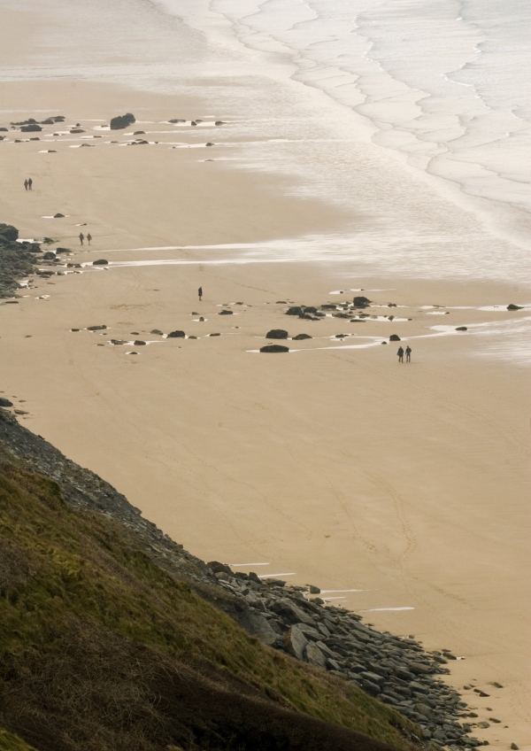 Distant walkers on a large, sandy beach