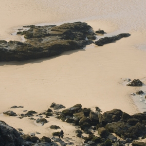 A large, empty, sandy beach with big rocks