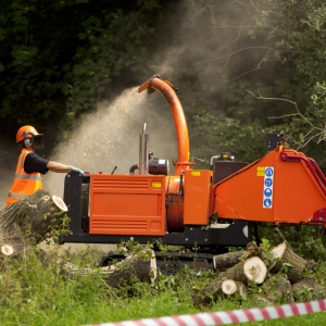 A forestry worker shredding branches and leaves in a shredder